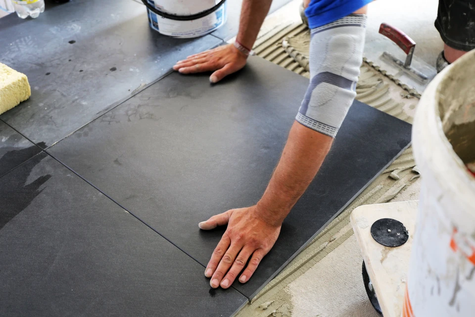 Artisan plombier en salopette installant ou réparant une cabine de douche moderne dans une salle de bain contemporaine