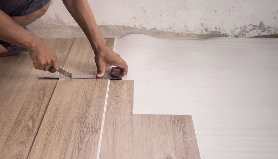 Artisan installateur de parquet en activité, agenouillé sur sol en cours de pose